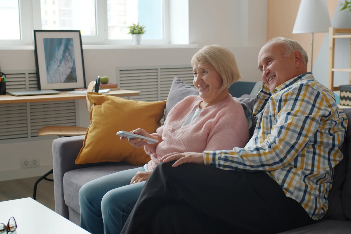 Ouder stel kijkt ontspannen tv via IPTV op de bank